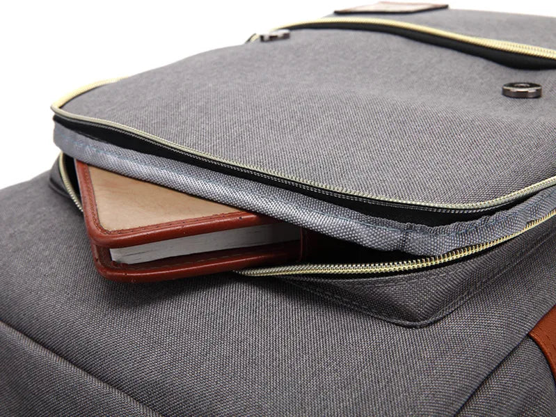 Gray backpack with a brown leather pocket on a white background