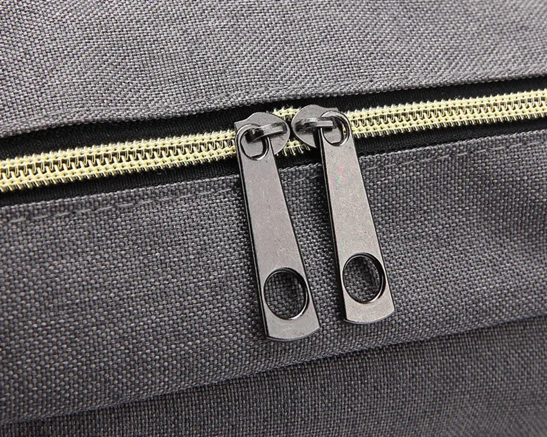 Close-up of a zipper on a gray bag with gold zipper pull.