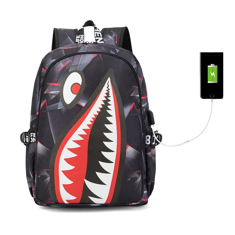 Backpack with shark mouth design and a charging cable attached on a white background