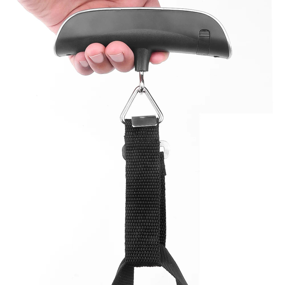 Hand holding a black luggage scale with a white background