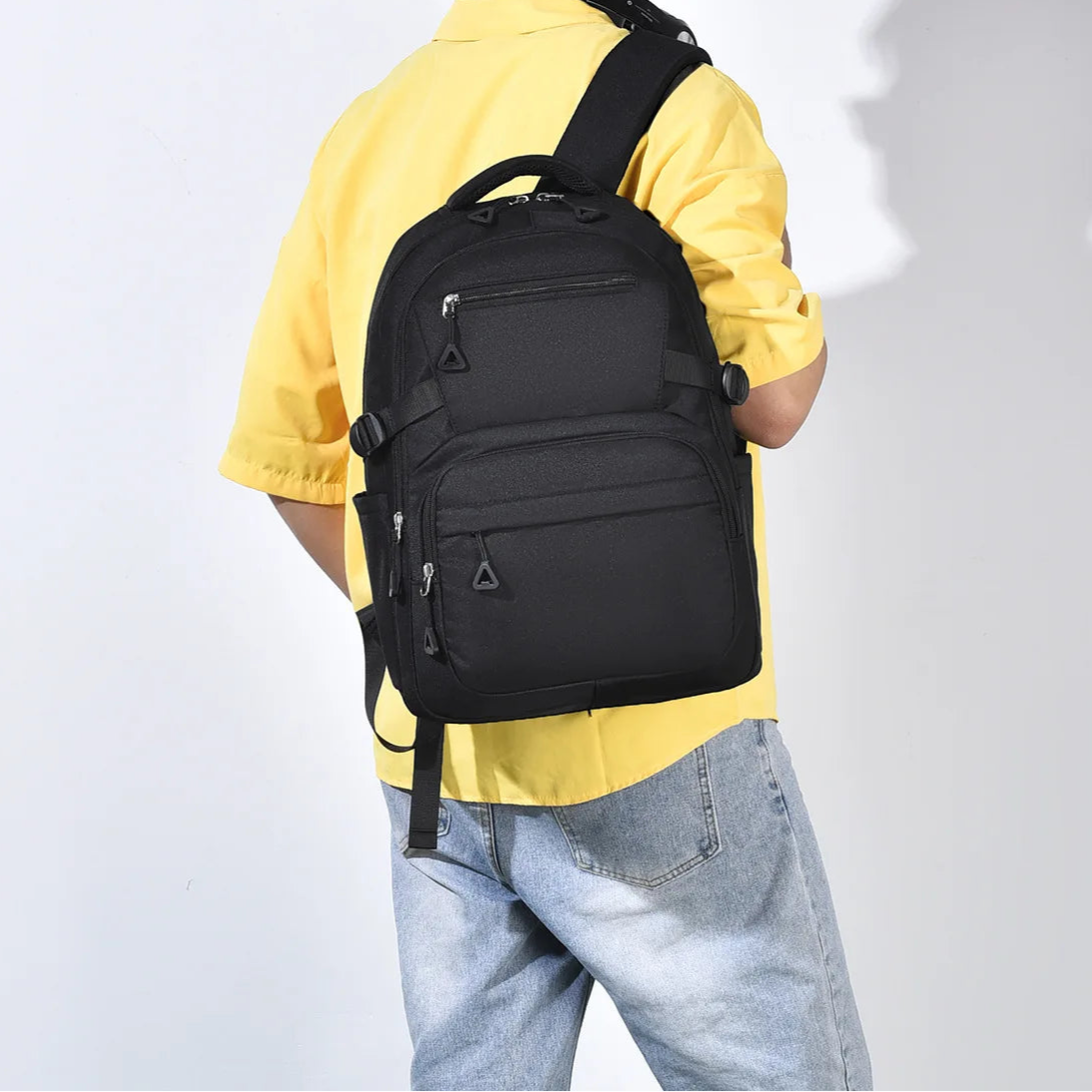 Person wearing a black backpack against a plain background
