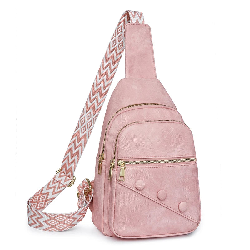 Pink suede sling bag with a patterned strap on a white background