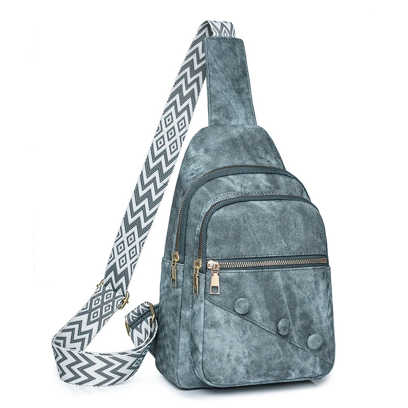 Gray suede sling bag with a patterned strap on a white background