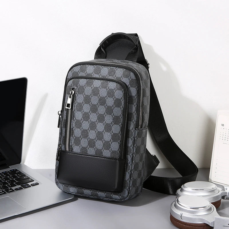 Gray checkered crossbody bag on a desk with a laptop and other items.