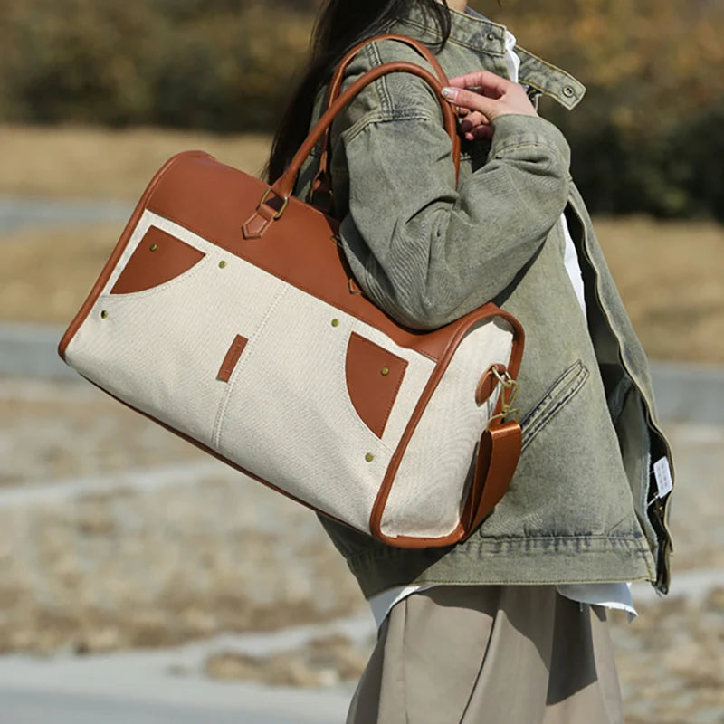 Person holding a beige and brown handbag outdoors
