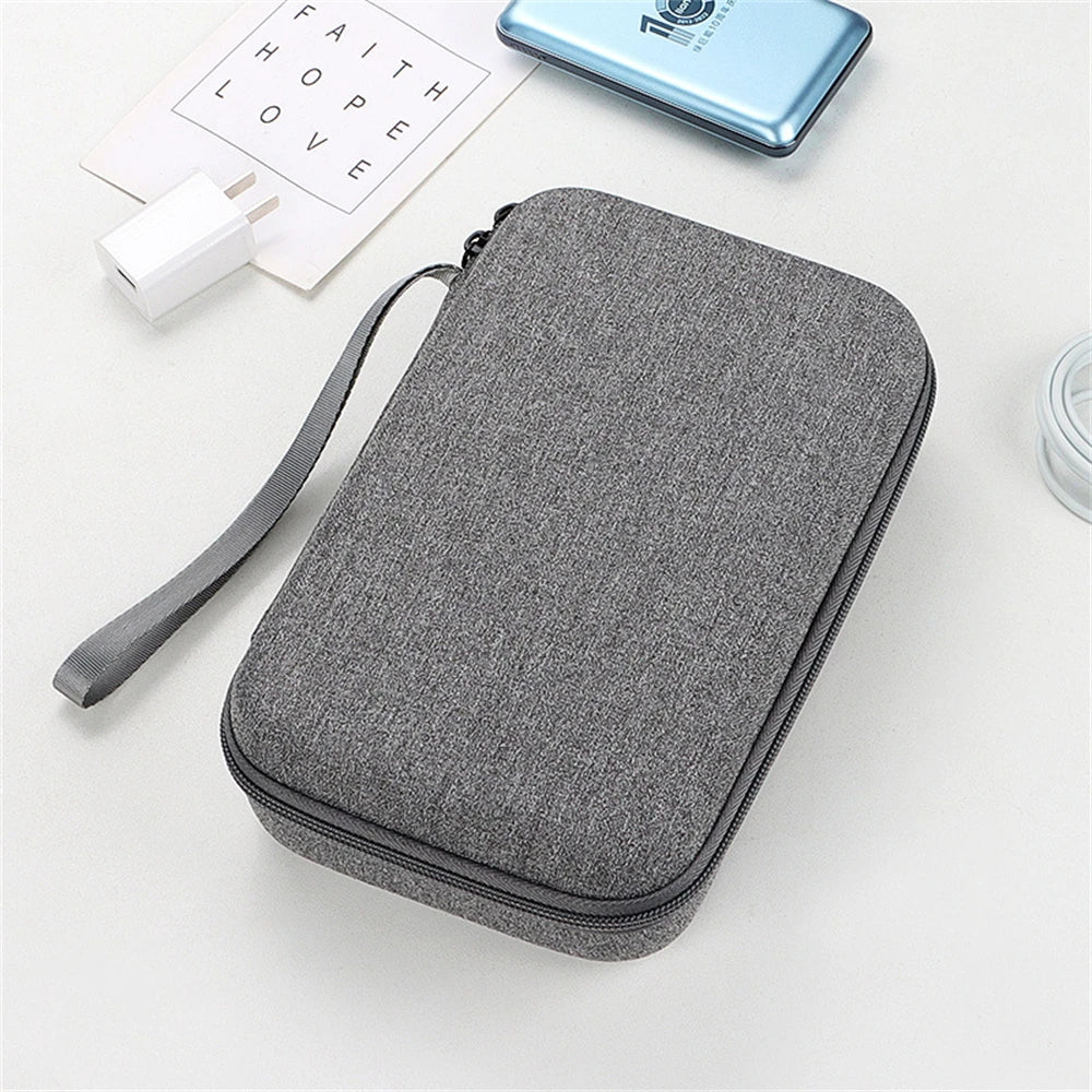 Gray travel case with a strap on a white surface with a phone and other items.
