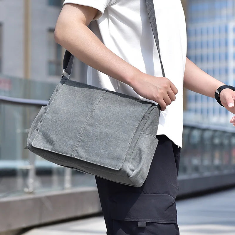 Person carrying a gray shoulder bag outdoors with blurred background