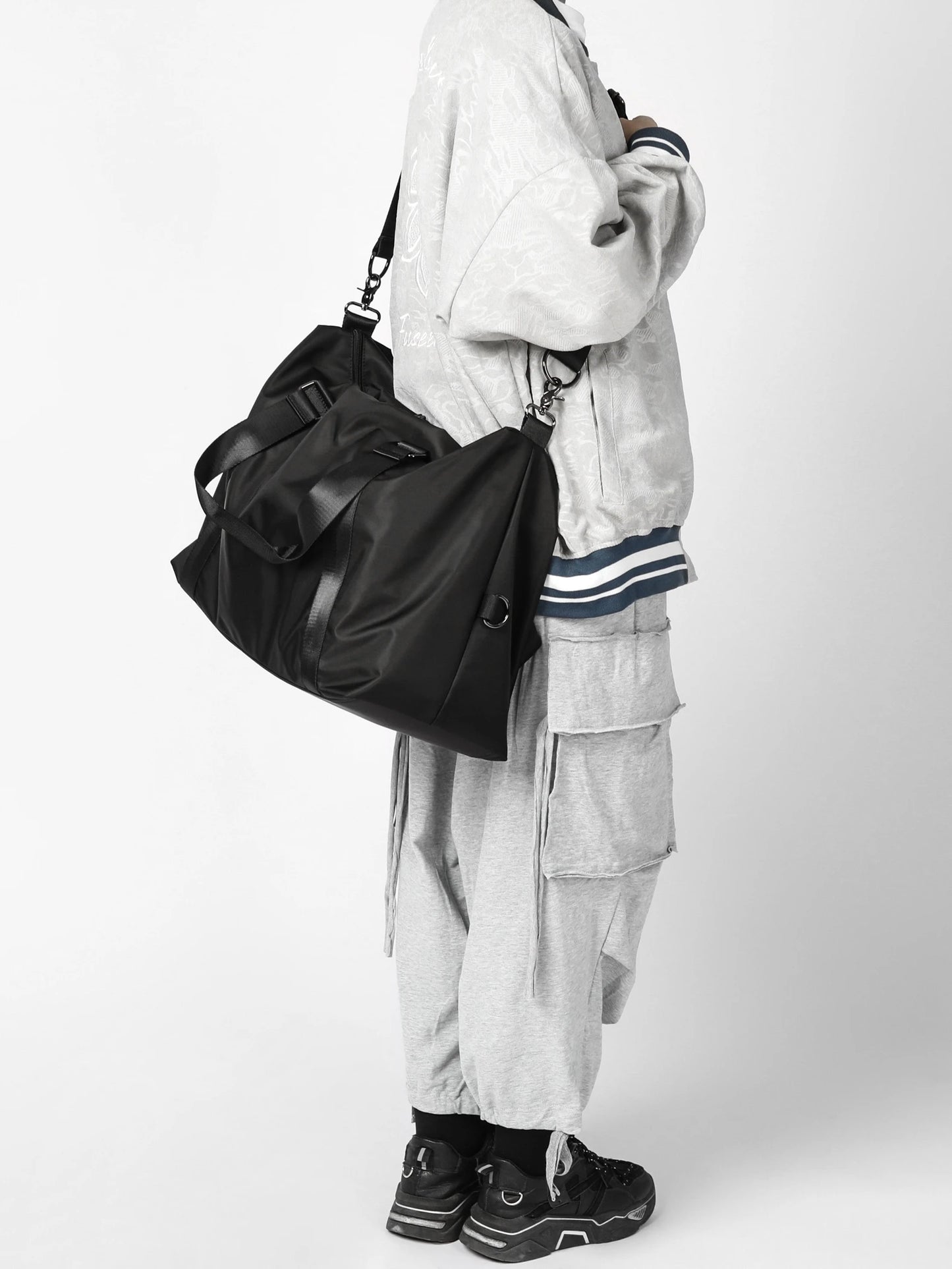 Person wearing a black bag and gray outfit on a white background