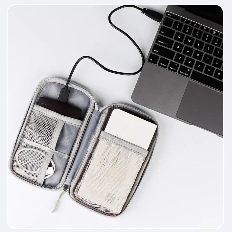 Travel organizer with USB cable, phone, and wallet next to a laptop on a white surface
