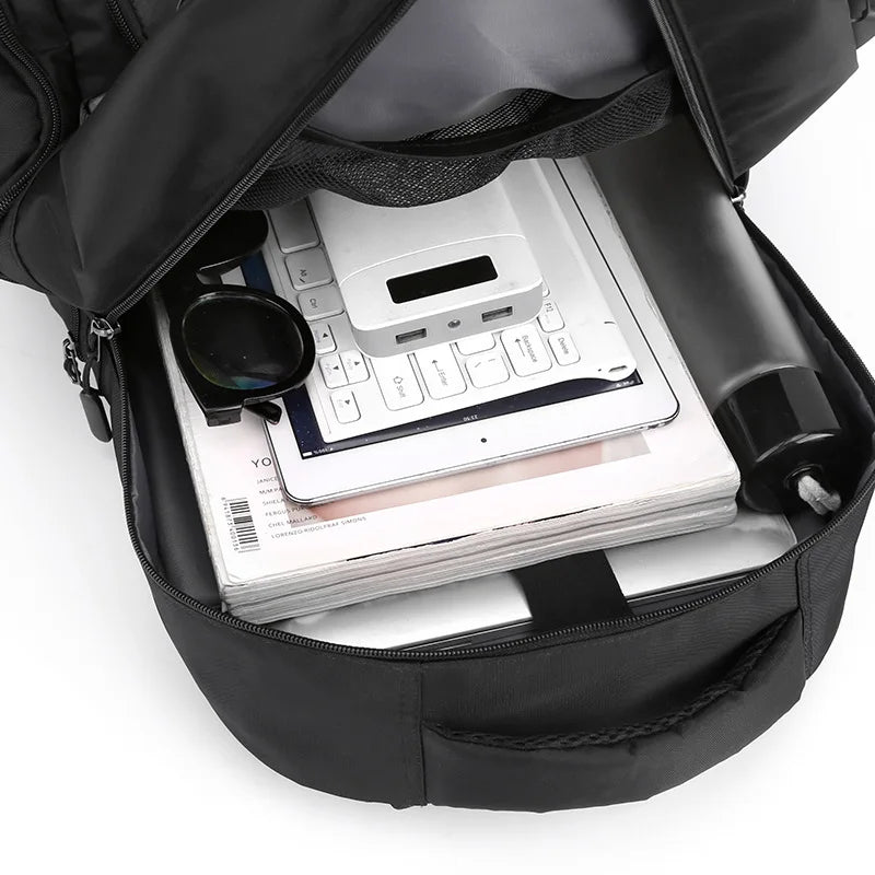 Black backpack with items including a keyboard, tablet, and power bank on a white background