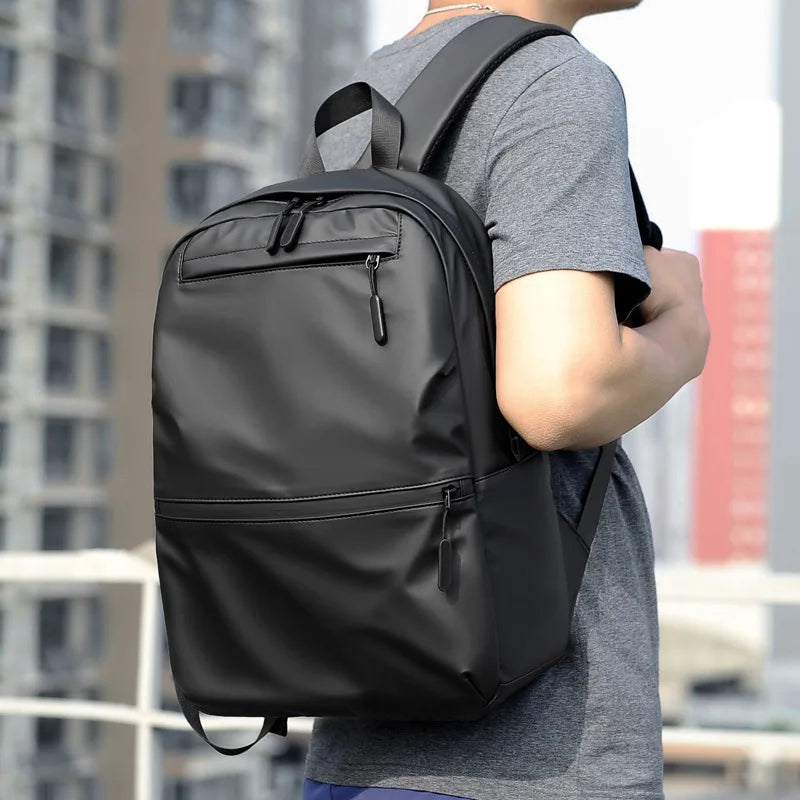 Stylish black laptop backpack on a person, perfect for students and travelers, made of waterproof materials.