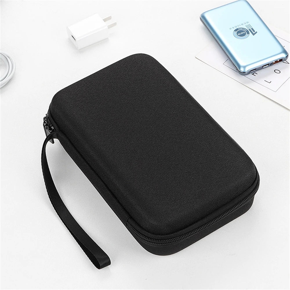 Black zippered case on a white surface with a power bank and phone in the background