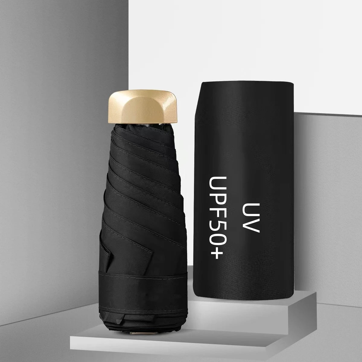 Black umbrella with gold cap and black sleeve labeled 'UPF50+' on a gray background