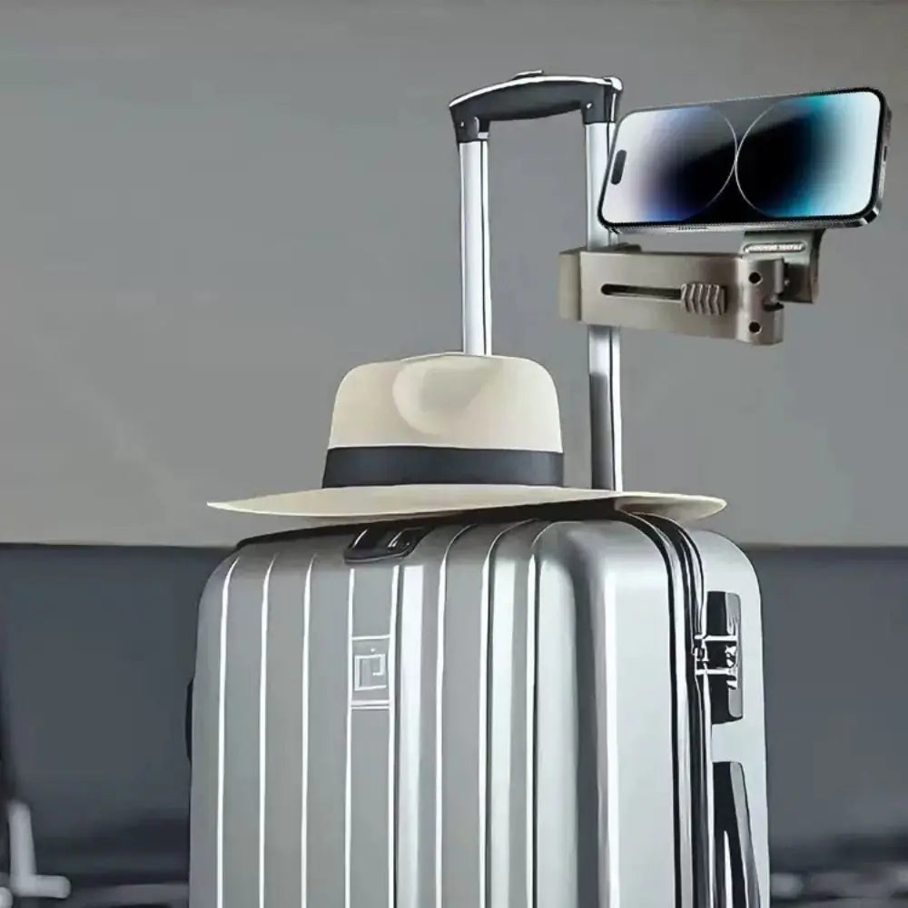 Silver suitcase with a hat on top and a smartphone attached to the handle.