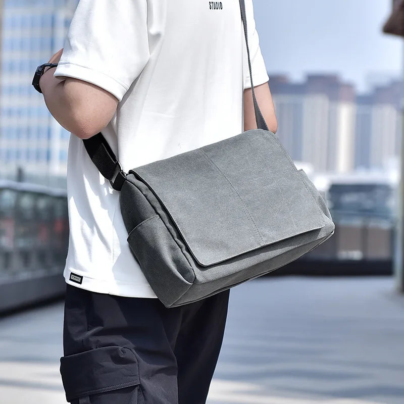 Person carrying a gray shoulder bag with a blurred cityscape background