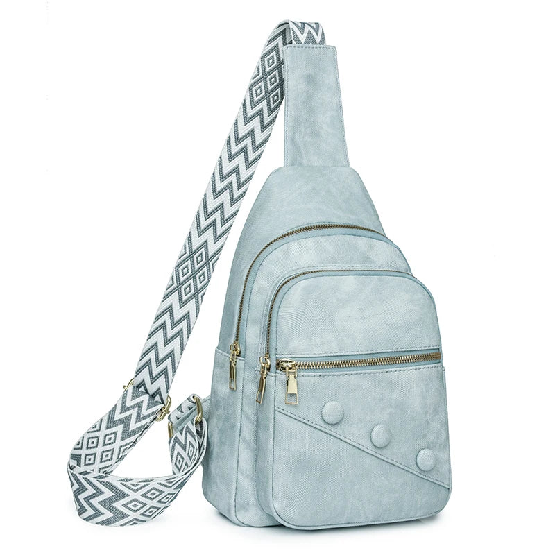 Light blue suede sling bag with a patterned strap on a white background