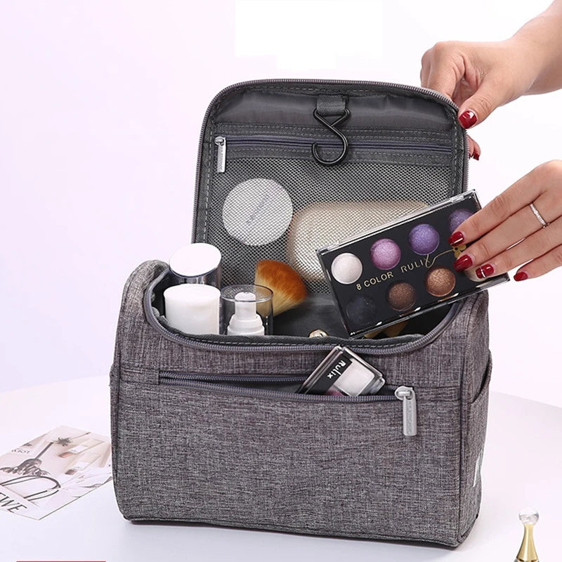 Gray toiletry bag with makeup items on a light purple background