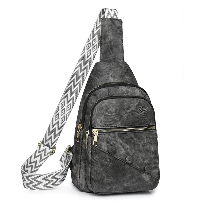 Gray suede sling bag with a patterned strap on a white background