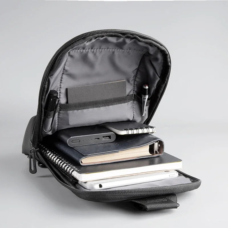 Black backpack open with electronic devices and notebooks on a gray background