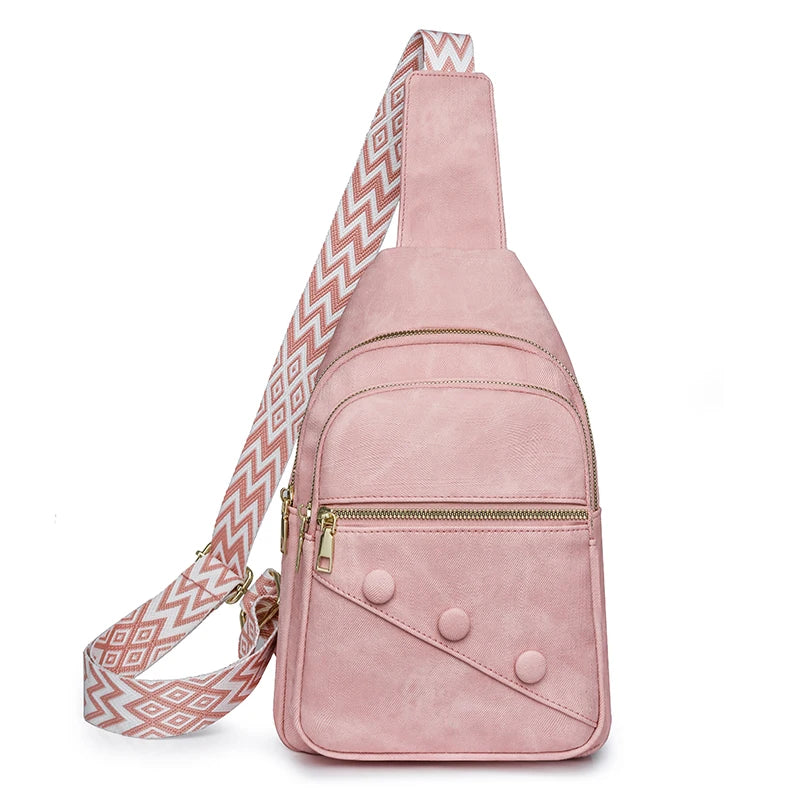 Pink suede sling bag with a patterned strap on a white background