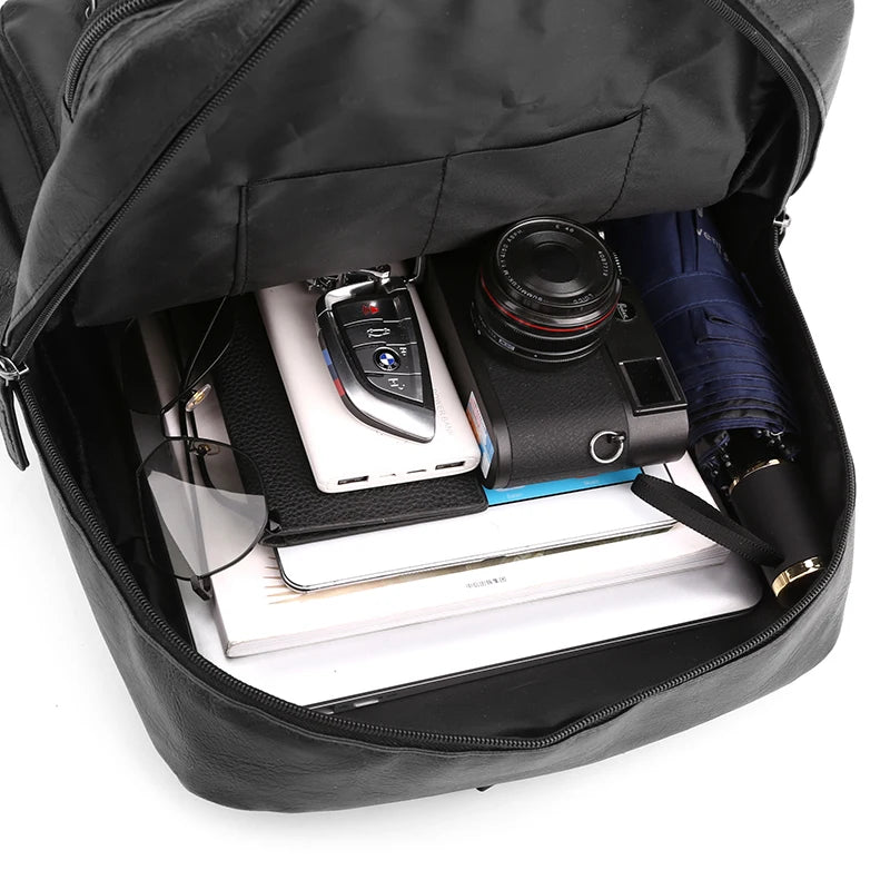 Black backpack with items including a camera, phone, and umbrella inside.