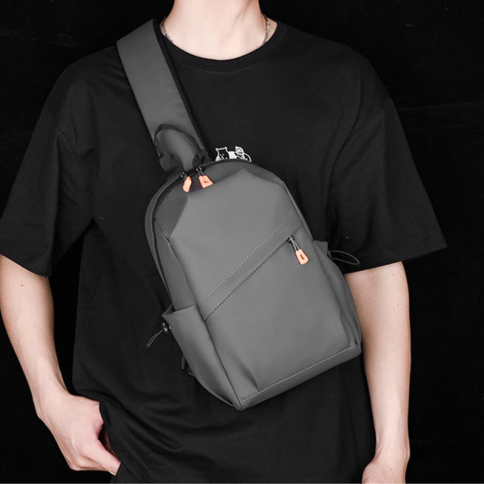 Person wearing a black t-shirt and a gray backpack against a black background