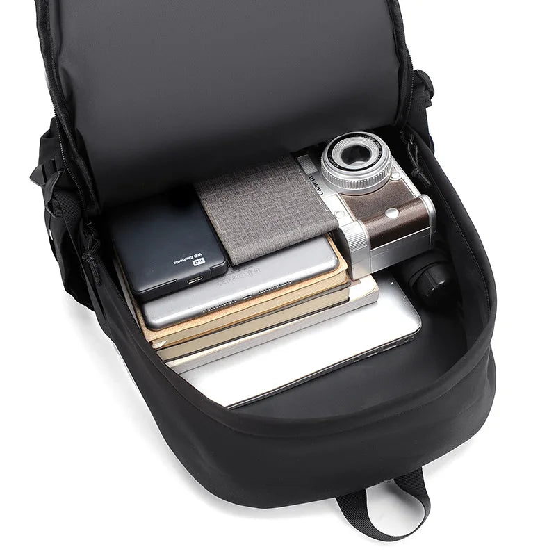 Black backpack with compartments containing a camera, phone, and books on a white background