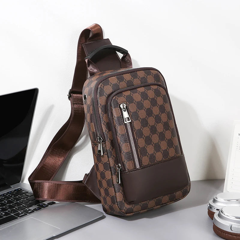 Brown checkered sling bag on a white surface with a laptop and lamp in the background