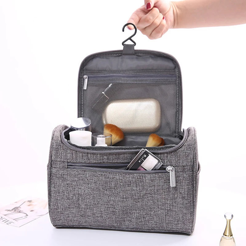 Gray toiletry bag with items on a white background