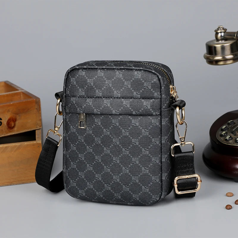 Gray patterned crossbody bag with gold accents on a gray background