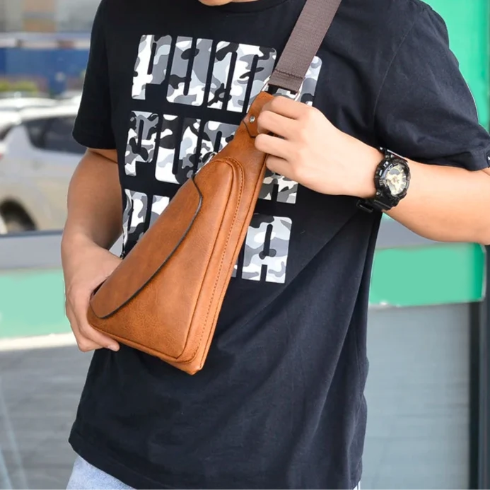 Person holding a brown leather bag with a black t-shirt featuring white text in the background