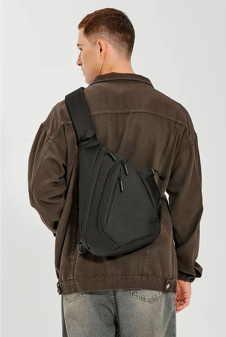 Man wearing a brown jacket with a black sling bag on a white background