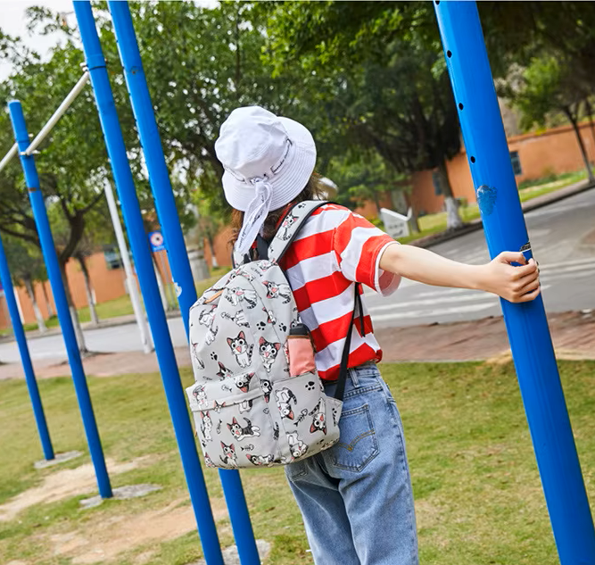 Person wearing a red and white striped shirt, blue jeans, and a patterned backpack on a playground.
