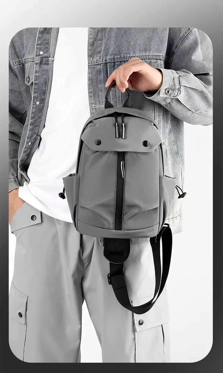 Person holding a gray backpack with a plain background