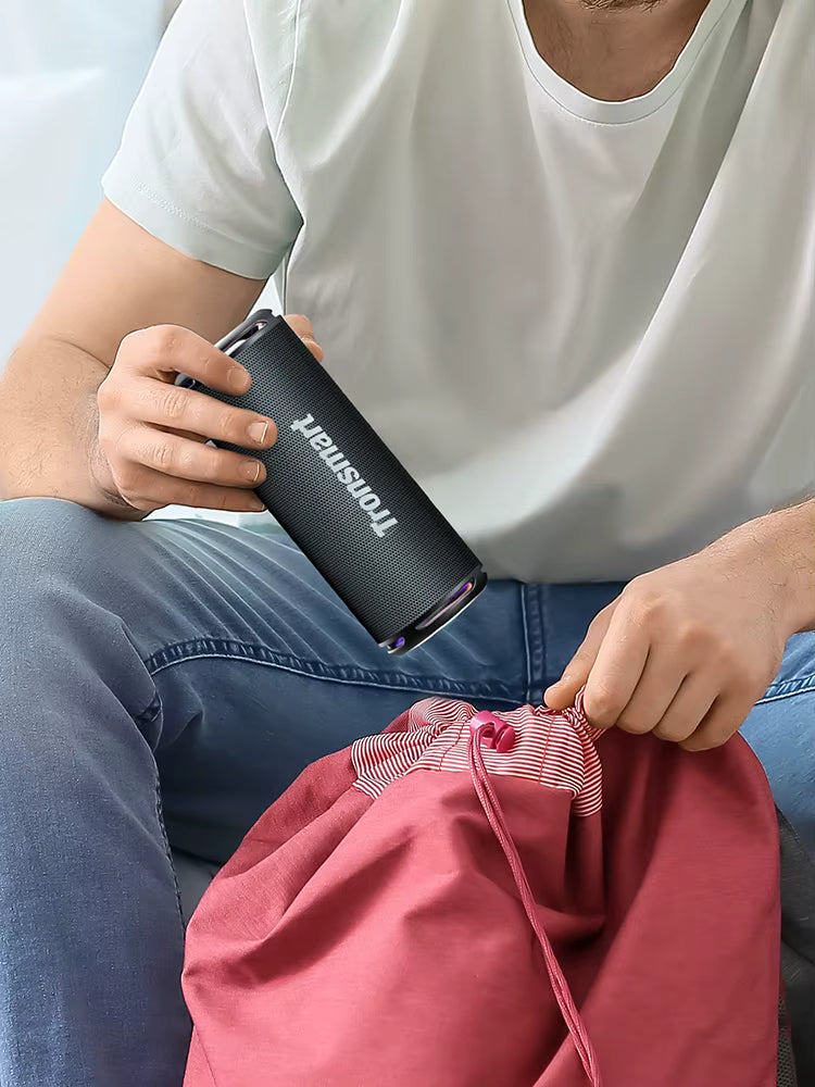 Person holding a black insulated mug with a brand logo, sitting on a pink bag.