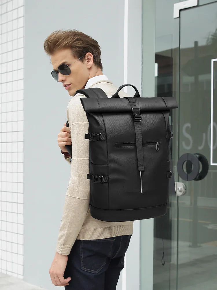 Man wearing a black roll-top backpack in an urban setting