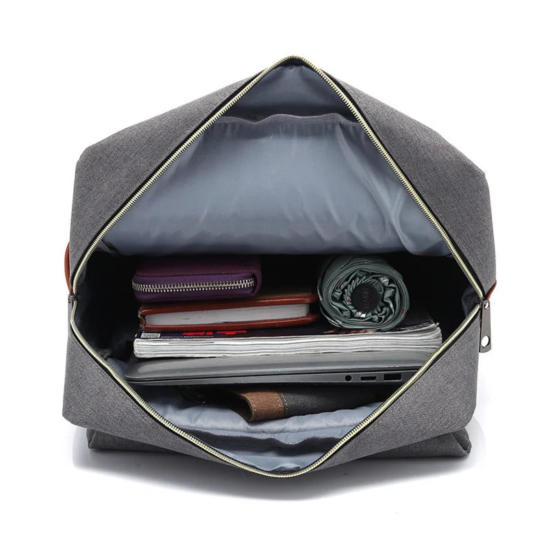 Gray backpack with open front compartment showing various items on a white background