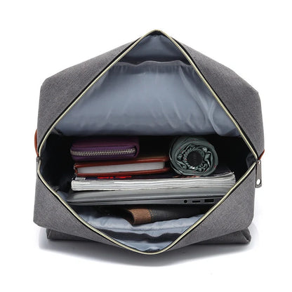 Gray backpack with open front compartment showing various items on a white background