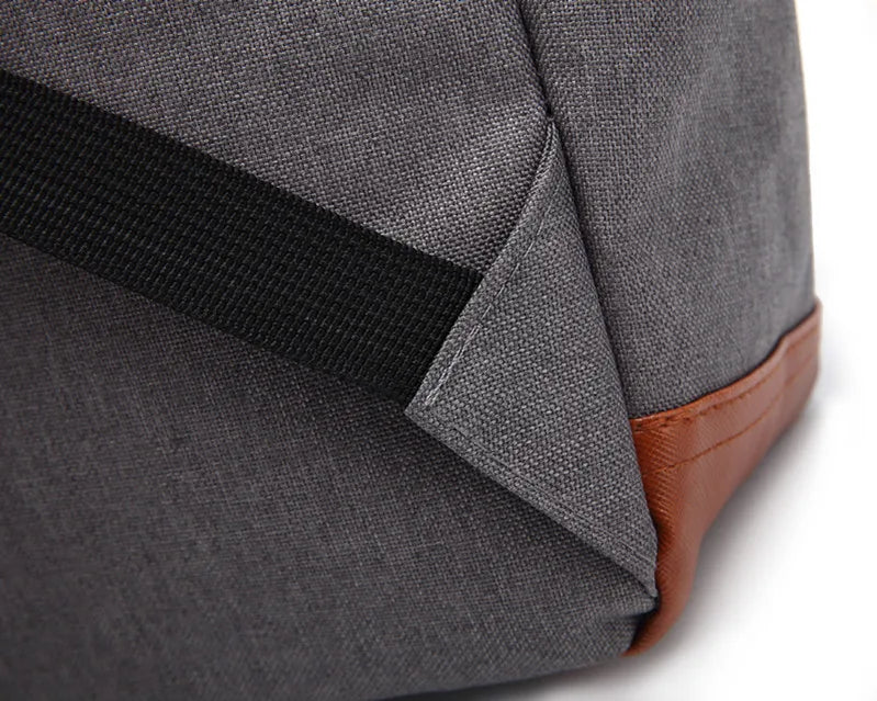 Close-up of a gray backpack with black strap and brown leather patch on a white background