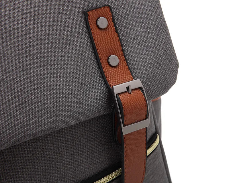 Gray backpack with a brown leather strap and metal buckle on a white background