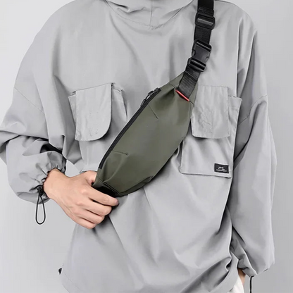 Person wearing a gray jacket with a green and black sling bag on a light gray background