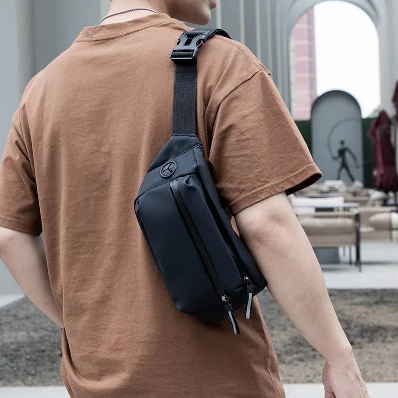 Person wearing a black sling bag over one shoulder with a blurred outdoor background