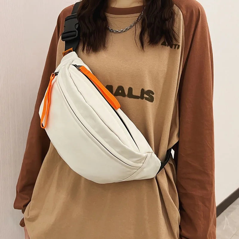 Person wearing a beige waist bag with orange accents on a neutral background