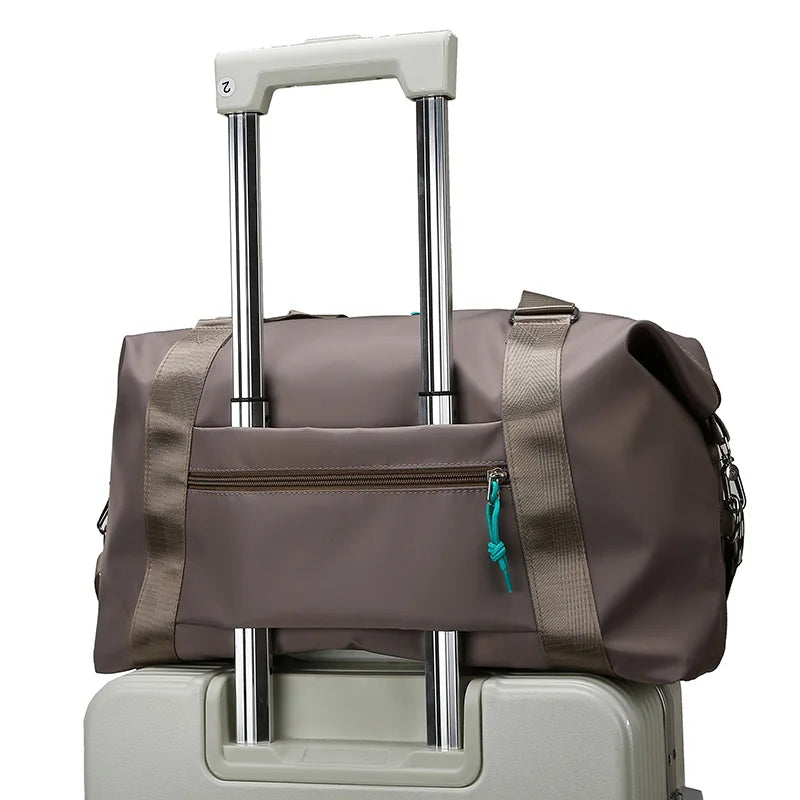 Brown duffel bag with wheels on top of a beige suitcase