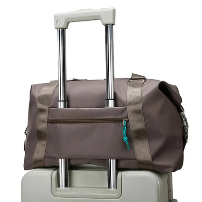 Brown duffel bag with wheels on top of a beige suitcase