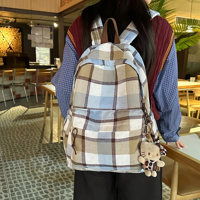 Person wearing a plaid backpack with a stuffed toy in an indoor setting