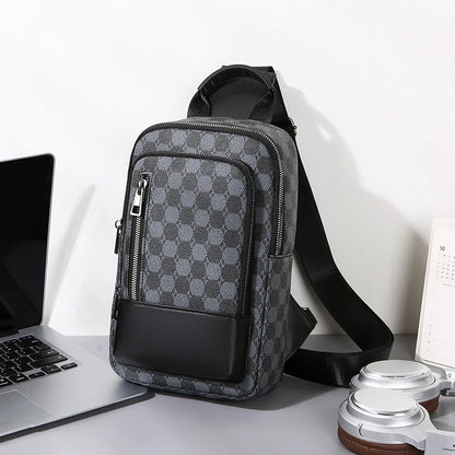 Gray checkered crossbody bag on a desk with a laptop and other items.
