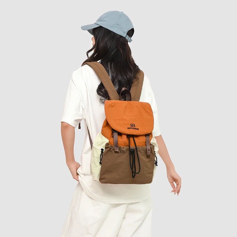 Person wearing a brown and orange backpack on a plain background