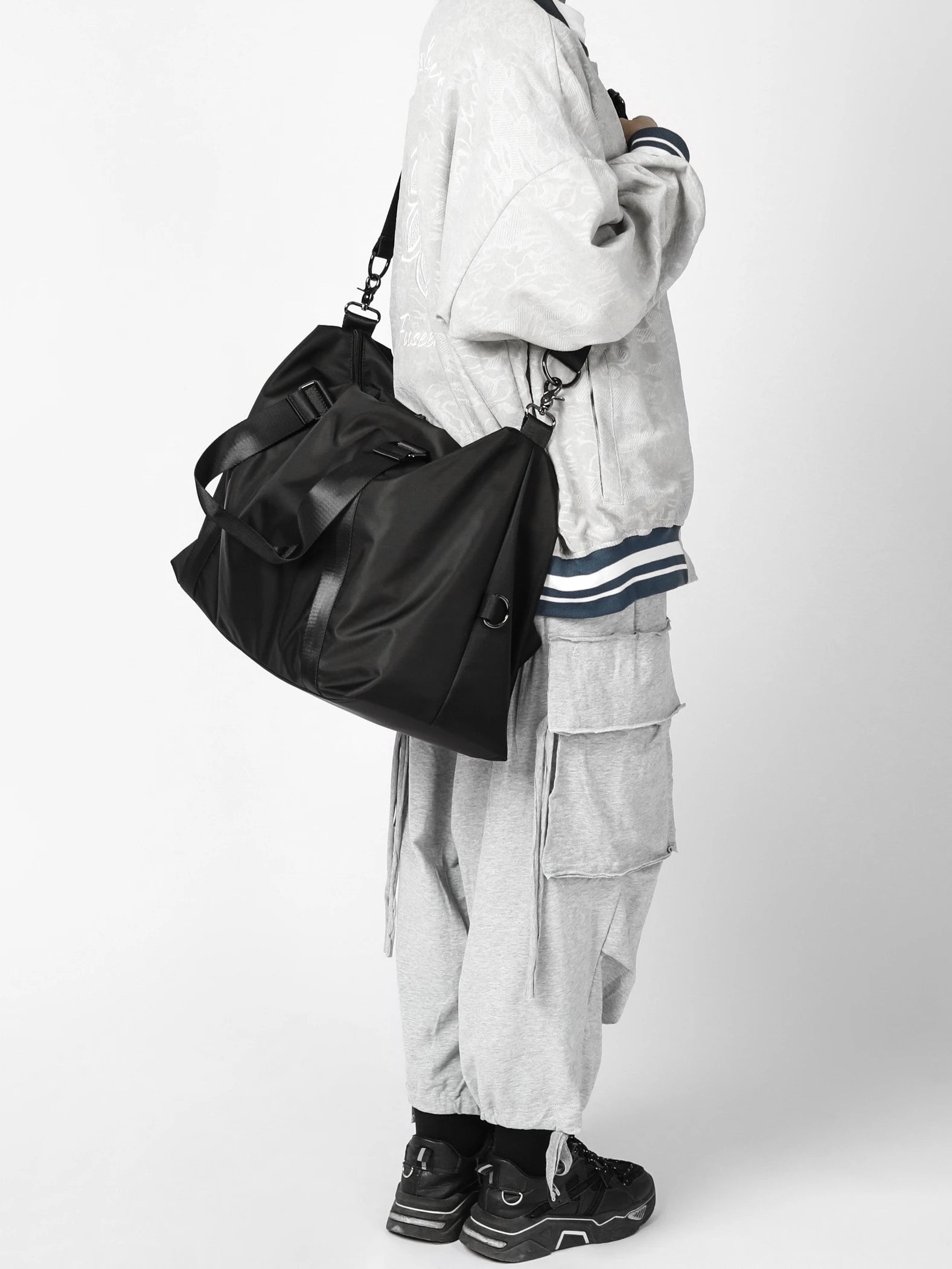 Person wearing a black bag and gray outfit on a white background