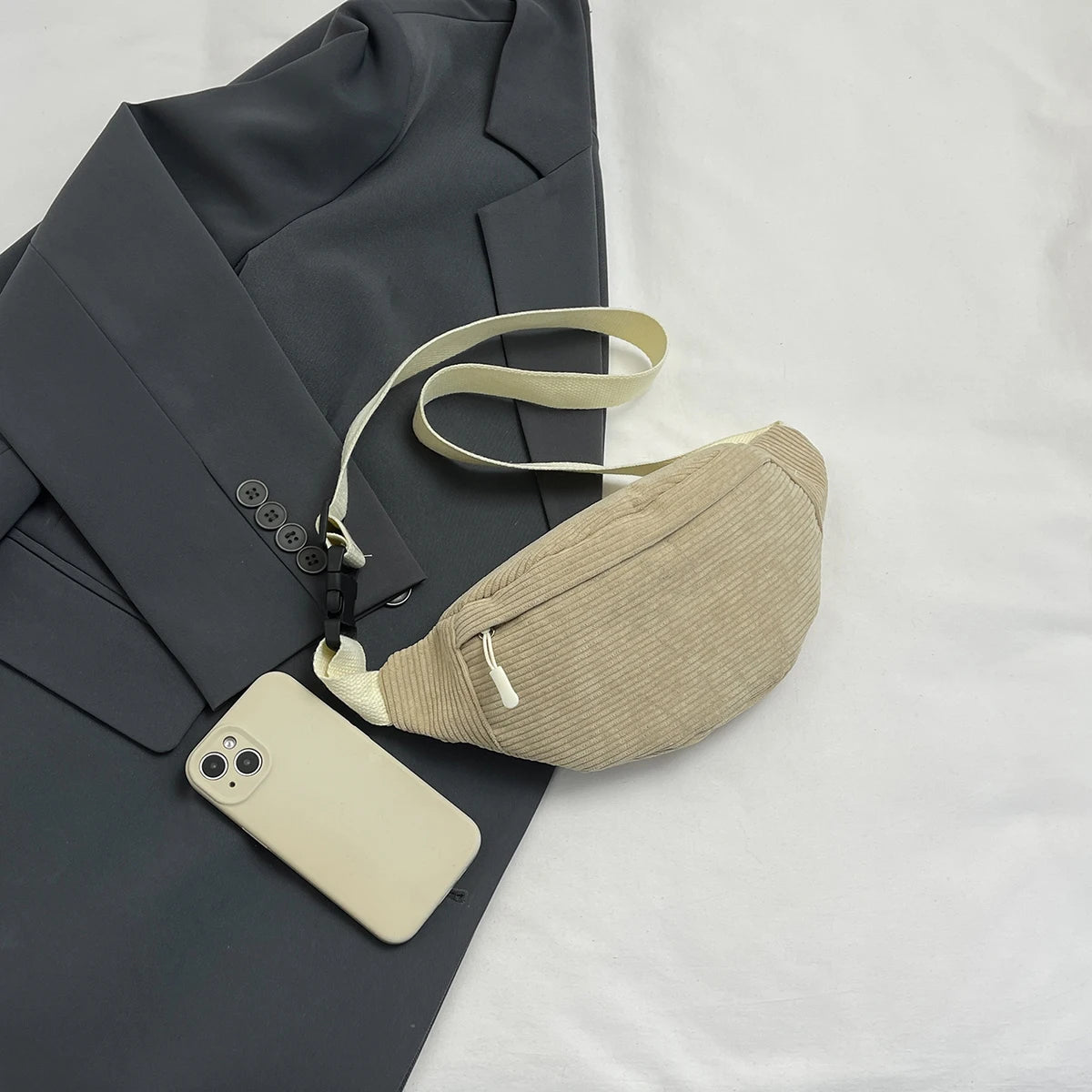 Beige waist bag with phone on a dark gray suit jacket and white background